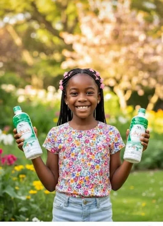 Smiling girl in a garden holding two bottles of Jinja Herbal Extract